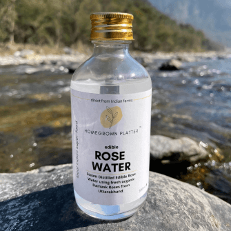 A bottle of 200ml edible rose water placed on a rock in a river